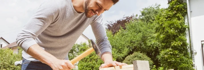 Person baut einen Nistkasten mit Hammer